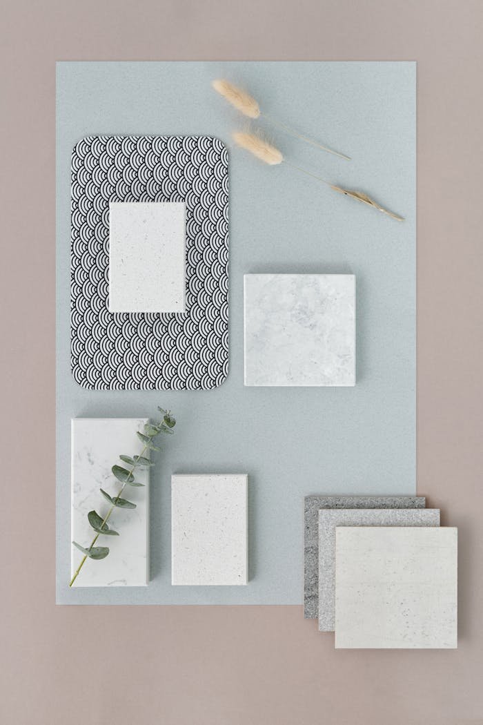 A minimalist flat lay showcasing marble tiles with a touch of greenery and natural elements.