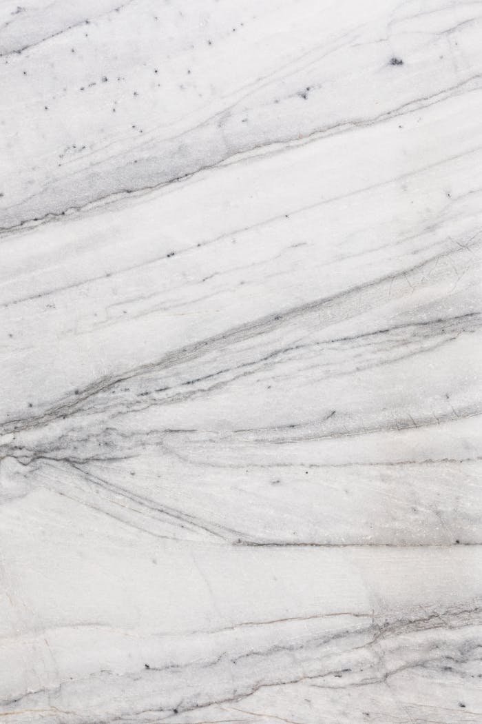 heros-img Close-up of a textured white marble surface with natural lines and patterns.