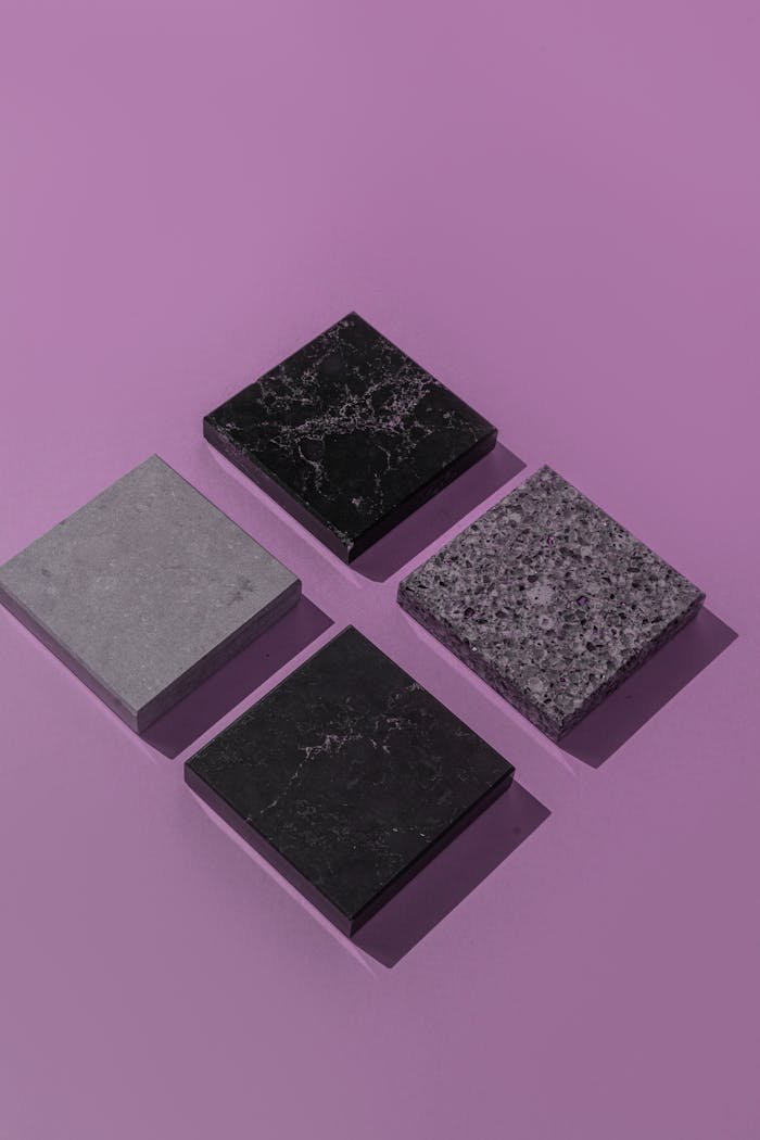 A geometric arrangement of stone tiles on a purple background showcasing texture and contrast.